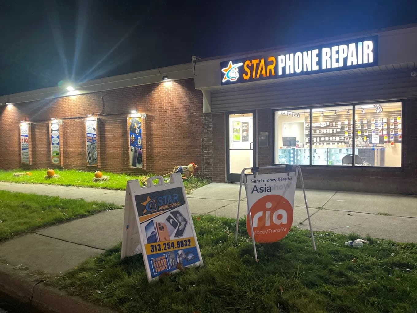 Star Phone Repair storefront at night with bright signs and advertisements for money transfers outside.
